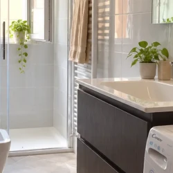 Bagno luminoso con mobile scuro e doccia sotto finestra